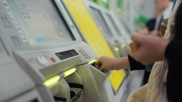 Tokyo, Japan - October 10, 2023 : Close up hands of woman tourist touching ticket machine for buying the train ticket at Tokyo, Japan. Woman buy train ticket at ticket machine public transportation