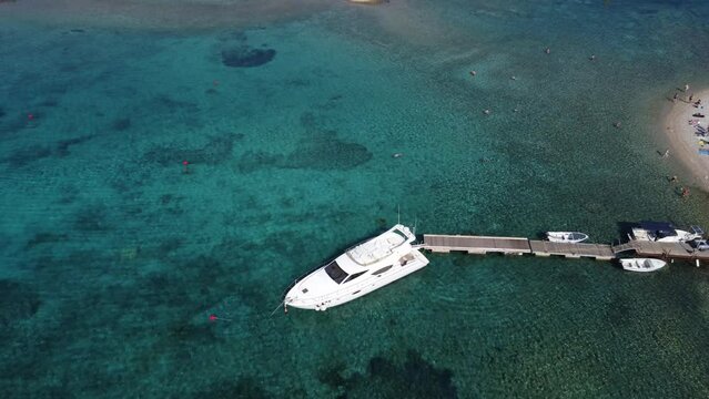 Yacht speedboat moored at beach jetty in Budikovac blue lagoon, croatia with people swimming