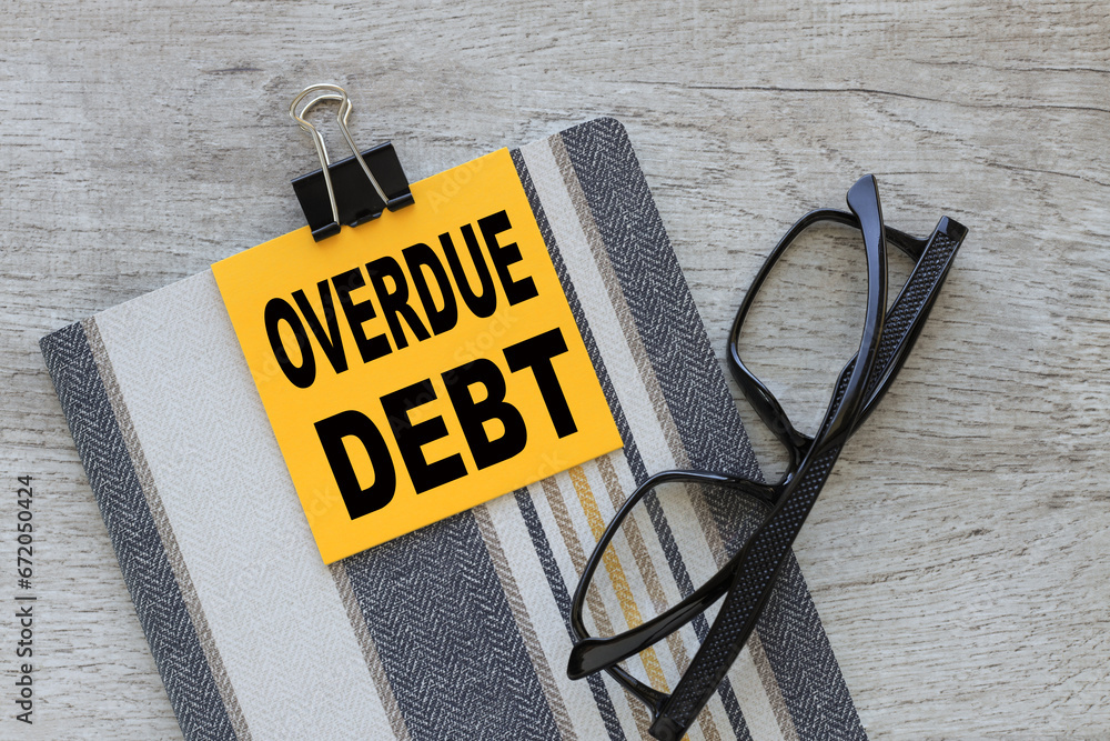 Poster overdue debt. yellow sticker with text attached to notebook