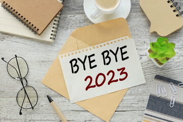 BYE, BYE 2023 on the middle table is an envelope with text torn from a pad of paper