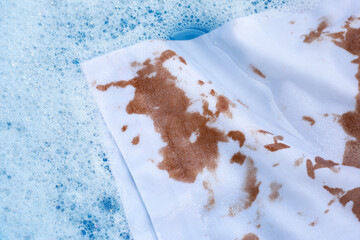 Dirty choclate stain on white shirt in water with detergent water dissolution, washing cloth