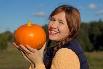 Fototapeta na wymiar Happy young woman in nature, countryside with pumpkin, concept autumn, harvest, village, halloween