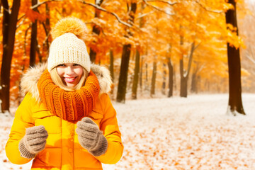 Blonde woman in yellow anorak enjoying autumn forest with snow