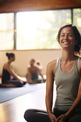 Fotobehang woman smiling in yoga class with people in the background. relax  © Uwe