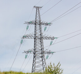 Metal electric poles against a gray sky with clouds