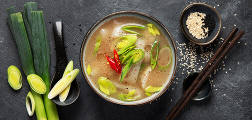 Bowl of leek soup with chili pepper on dark background. Food concept