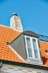 Chimney chute, window and sunroof skylight designed on house building outside against blue sky...