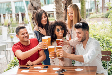 Joyful multiethnic friends clinking with beer