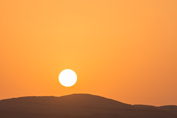 bright sun with orange sky over a black mountain on vacation