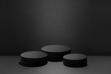 Abstract three black round podiums with light of spotlight for cosmetic products, mockup on black...