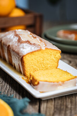 Popular biscuit dessert called Pound cake with white topping, served with oranges on rustic wooden background