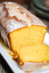 Popular biscuit dessert called Pound cake with white topping, served with oranges on rustic wooden background
