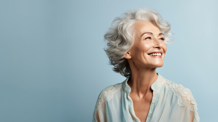 Buoyant woman in her 60s with silver hair against pale blue backdrop