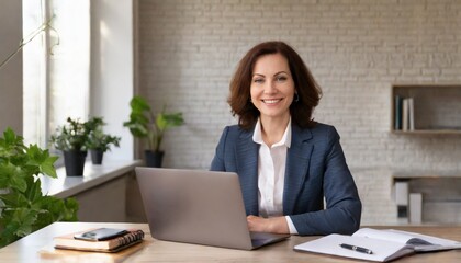 Happy smiling mature mid aged professional business woman manager executive or lawyer attorney looking at camera at workplace working on laptop computer technology in office sitting at desk