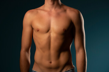Fototapeta premium the torso of a young athletic guy. concept: the male body after exercise and diet. men's health: shaved breasts on a dark background