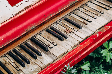 Close up of an old red piano with shabby keys on the street in London