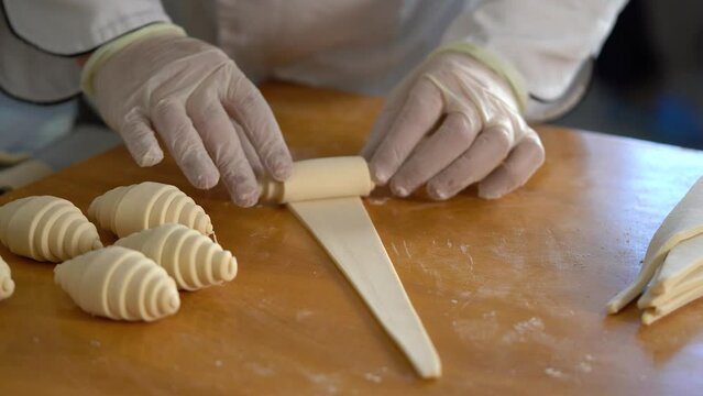 A French pastry chef rolls out croissant dough on the table