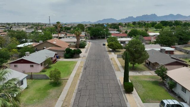 American neighborhood in the Southwest. Aerial reverse dolly shot over street lined by houses and homes.