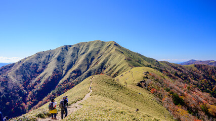 剣山の中腹から見た次郎笈の景色と稜線歩きをする登山者