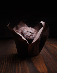 Chocolate cupcake on a dark background. Muffin with chocolate chips on a wooden surface.