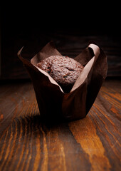 Chocolate cupcake on a dark background. Muffin with chocolate chips on a wooden surface.