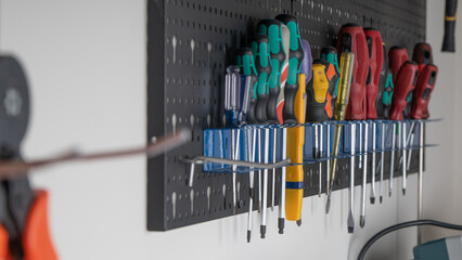 Selective focus of various screwdriver tools hanging on the wall and kept in holders in the garage