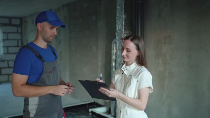 Female client signs a contract with a builder who will do finishing repairs in the apartment. The male repairman negotiates with the customer