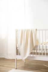 Fototapeta na wymiar Muslin baby blanket hanging on child's bed in nursing room