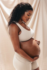 Loving mother-to-be holding her belly in studio: Celebrating maternity and motherhood - obrazy, fototapety, plakaty