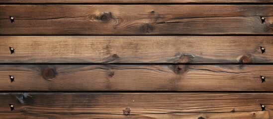 Close up of the textured surface of an aged wooden board with nail heads in the background