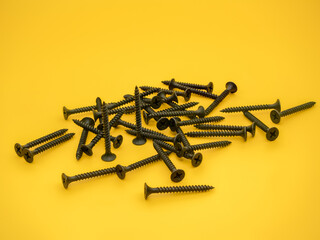 black powder coated dry wall screws isolated on a plain background - obrazy, fototapety, plakaty