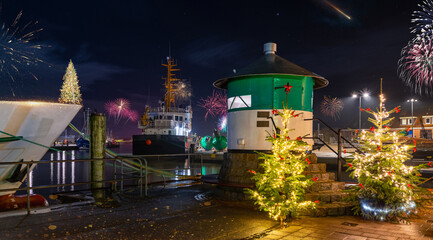Green pier light, cristmas trees and fireworks in the fishing port of Büsum on the German North...