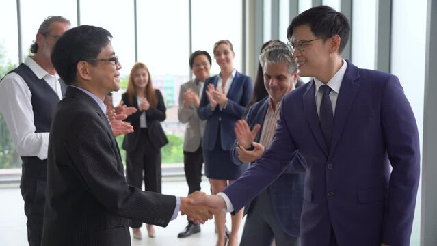 two asian business man handshake and Multiracial group of diversity business people in row applauding or clapping hands congratulate to success achievement goal with colleague team .