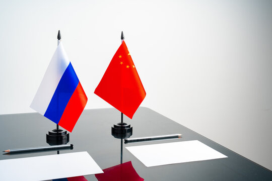 Russian and Chinese flags on negotiation table - Powered by Adobe