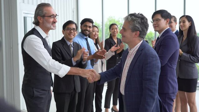 two senior business man handshake and Multiracial group of diversity business people in row applauding or clapping hands congratulate to success achievement goal with colleague team .
