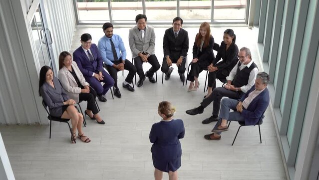 group of diverse business team building sitting on chairs in circle meeting audience applauding to speaker in seminar conference . Multicultural business people cheering and clapping hands to speaker