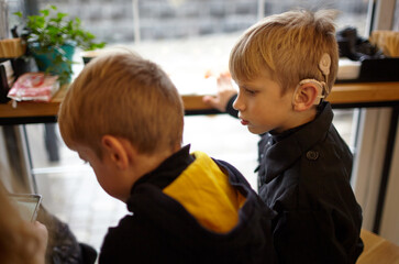 Boy have a Hearing Aids. Two twin brothers in a cafe. Selective focus, shallow depth of field
