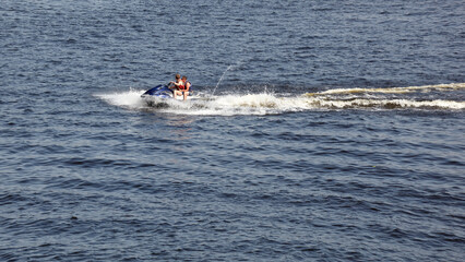 Two men jumps on the  water scooter above the water. Men speeding on powerboat on lake during summer vacation