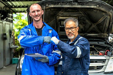 Young Caucasian car mechanic man doing bump fist hands with senior technician during working in car...