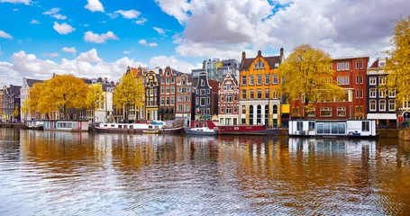 Foto auf Acrylglas Amsterdam, Netherlands. Panoramic view of channels in amsterdam city. Dancing houses. River Amstel. Old european landmark. City autumn fall landscape with blue sky clouds © Yasonya