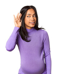 Fototapeta premium Young Filipina woman expecting a baby in studio trying to listening a gossip.