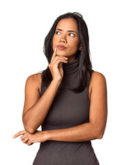 Young Filipina with long black hair in studio looking sideways with doubtful and skeptical expression. - obrazy, fototapety, plakaty
