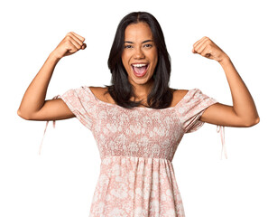 Young Filipina with long black hair in studio showing strength gesture with arms, symbol of feminine power
