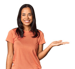 Young Filipina with long black hair in studio showing a copy space on a palm and holding another...