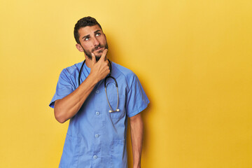 Young Hispanic male nurse Young Hispanic male nurse poses confidently looking sideways with doubtful and skeptical expression.< mixto > - obrazy, fototapety, plakaty