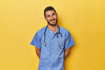 Young Hispanic male nurse Young Hispanic male nurse poses confidently happy, smiling and cheerful.<...