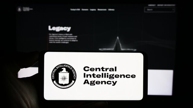 Stuttgart, Germany - 10-29-2023: Person holding cellphone with logo of US Central Intelligence Agency (CIA) in front of webpage. Focus on phone display.