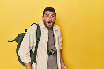 Young Hispanic travel photographer poses screaming very angry and aggressive.