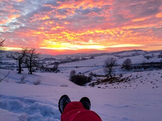 Hiking boots and view of amazing sunset over snowcapped mountains