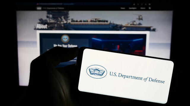 Stuttgart, Germany - 10-29-2023: Person holding smartphone with logo of United States Department of Defense (DoD) in front of website. Focus on phone display.
